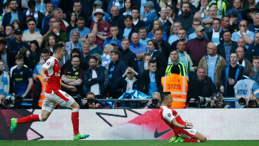 Alexis Sanchez slides in front of Manchester City fans