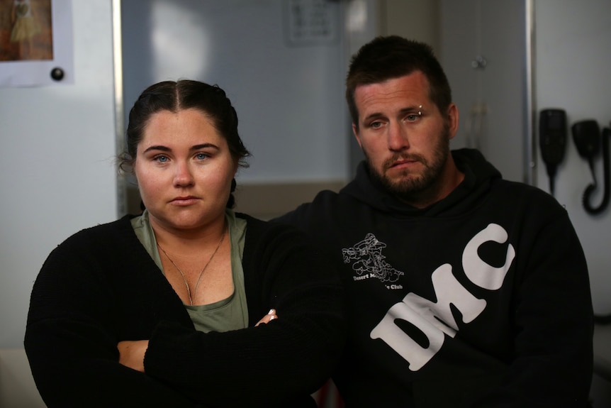 A man and woman sitting inside a dark room in the back of a truck both very emotional.