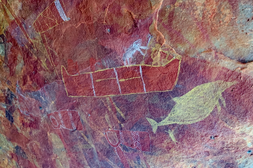 Rock art featuring a boat and a fish in a cave