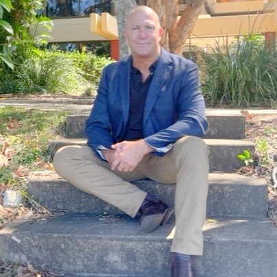 Man in business attire sitting on concrete steps in a garden like setting