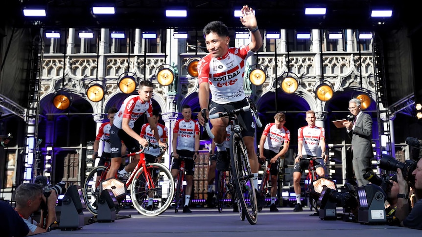 Caleb Ewan mounts his bike as he descends a ramp on the podium at the Tour de France.