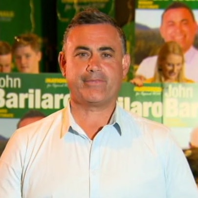 A man with a tight-lipped half-smile stands in front of a crowd of political supporters.