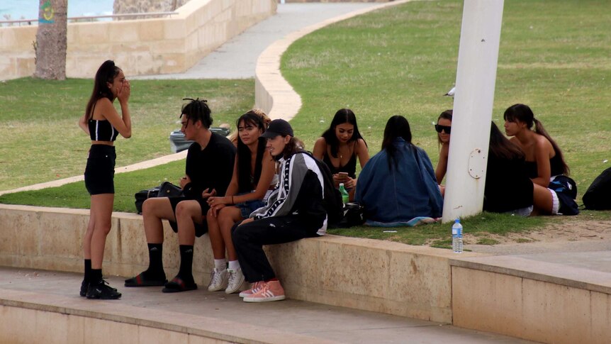A group of teenagers sitting on a wall.