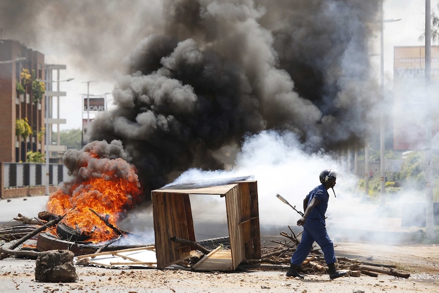 A policeman walks in front of a burning barricade in Burundi after a coup was announced