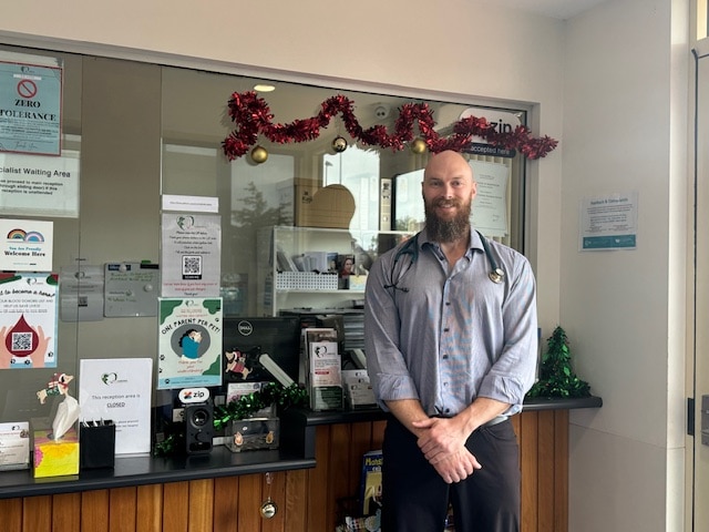 A bald man in a vet's uniform smiles.