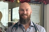 A bald man in a vet's uniform smiles.