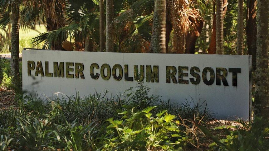 A sign saying 'Palmer Coolum Resort' with palm trees and shade behind it.