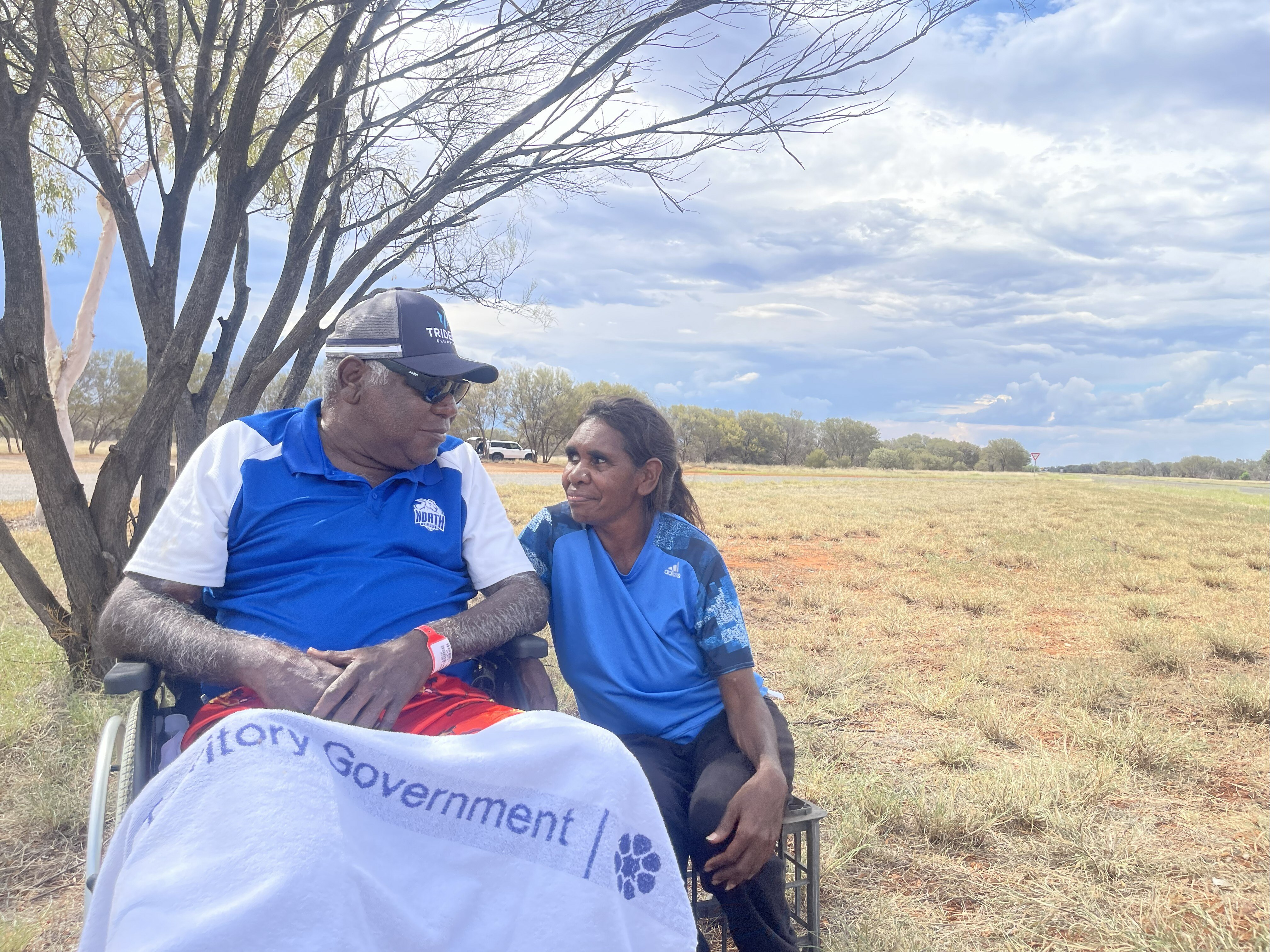 Un hombre en silla de ruedas mira a una mujer a su lado, se sonríen.