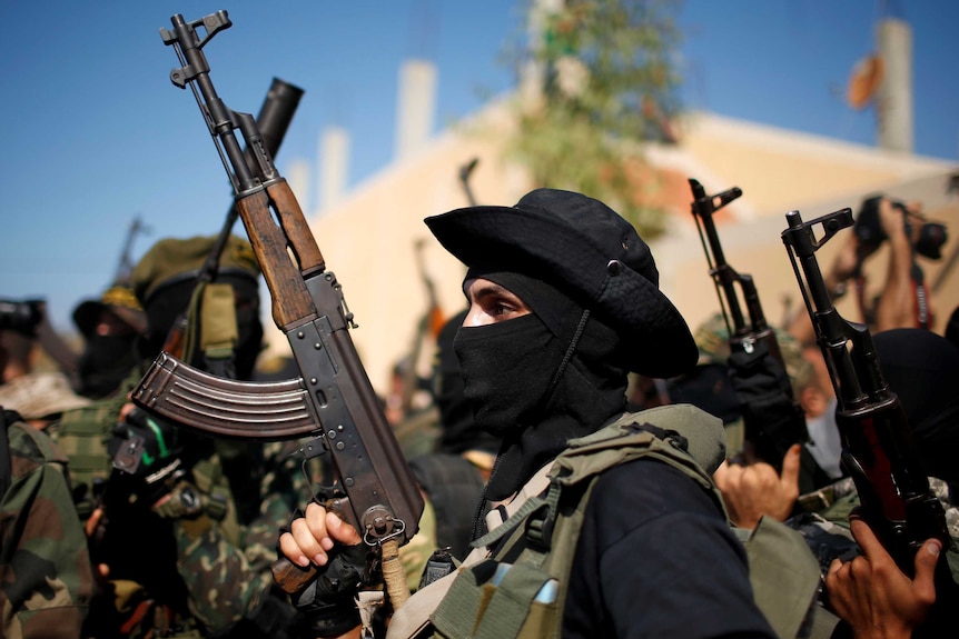 Palestinian militant holds up rifle at funeral of comrade killed in Israeli tunnel blast