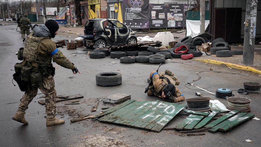 Ukrainian servicemen look under debris in a street for booby-traps. 