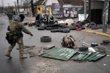 Ukrainian servicemen look under debris in a street for booby-traps. 