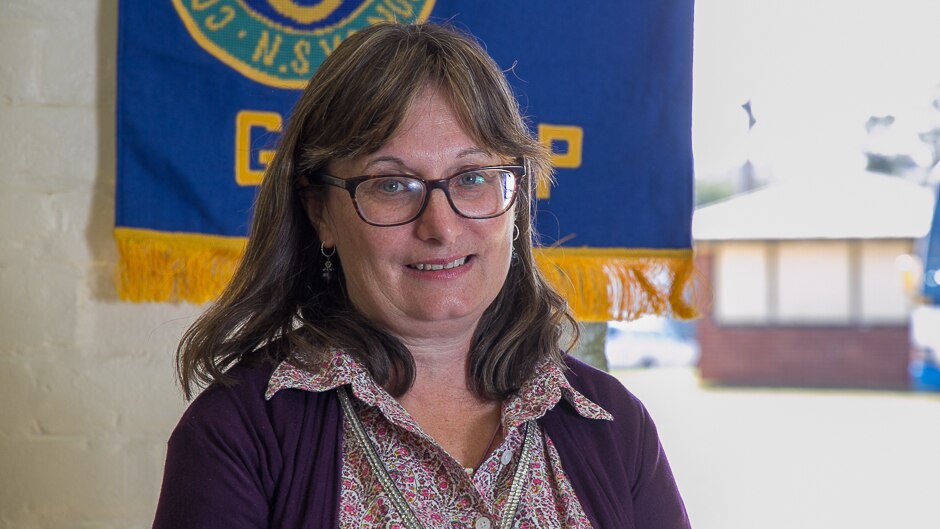 A woman close up with a blue and yellow banner in the background