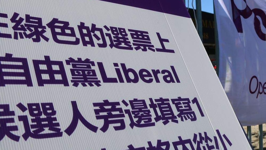 A close-up photograph of a poster with Chinese characters and the word 'Liberal', in a purple and white colour scheme.