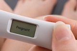 A woman holding a pregnancy test.