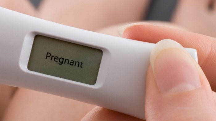 A woman holding a pregnancy test.