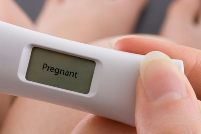 A woman holding a pregnancy test.