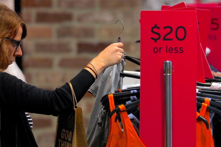A shopper looks at clothes on sale