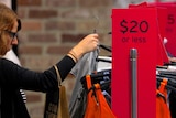 A shopper looks at clothes on sale