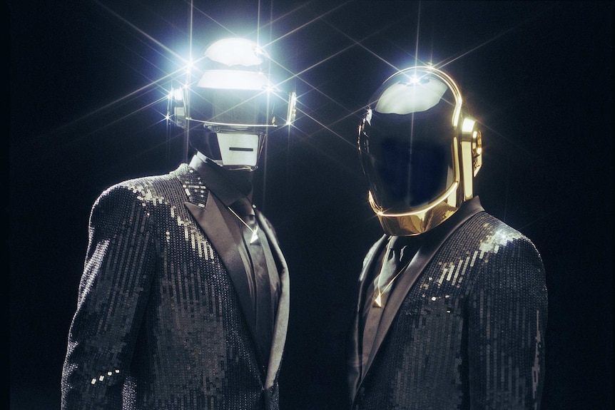 Daft Punk, wearing their trademark futuristic helmets with sequinned black dinner jackets.