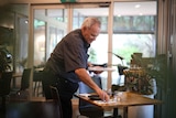 A man sets a table in a restaurant.