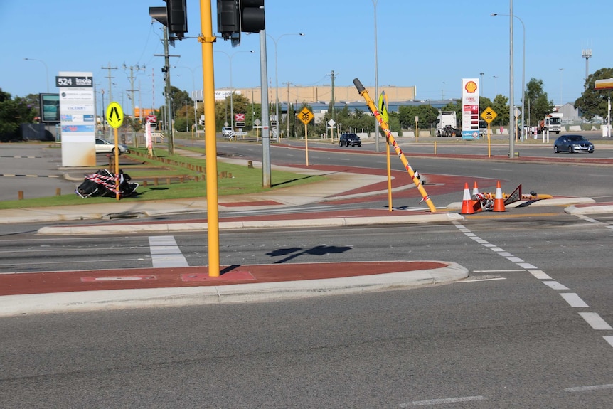 A traffic light pole and give way sign are bent over at the scene of the crash.