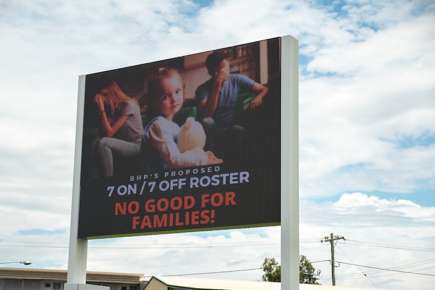 A billboard picturing a family as part of a union campaign against BHP's proposed roster change, Moranbah, November 2021.