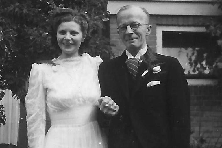 A black and white photo of a bride and groom holding hands and smiling