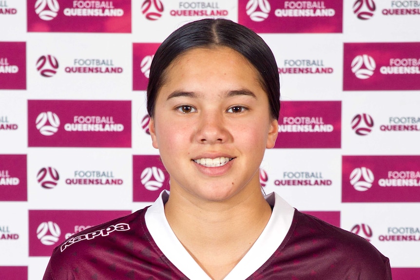 A portrait image of Under 17 player Ellen Gett in front of Football Queensland banner