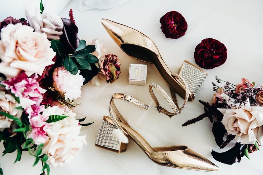 Flowers, shoes and a little box sit on a white background