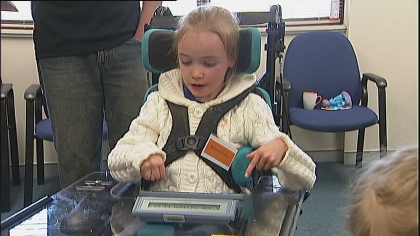 Girl in wheelchair uses keyboard to communicate while carer watches. File footage July 2012.