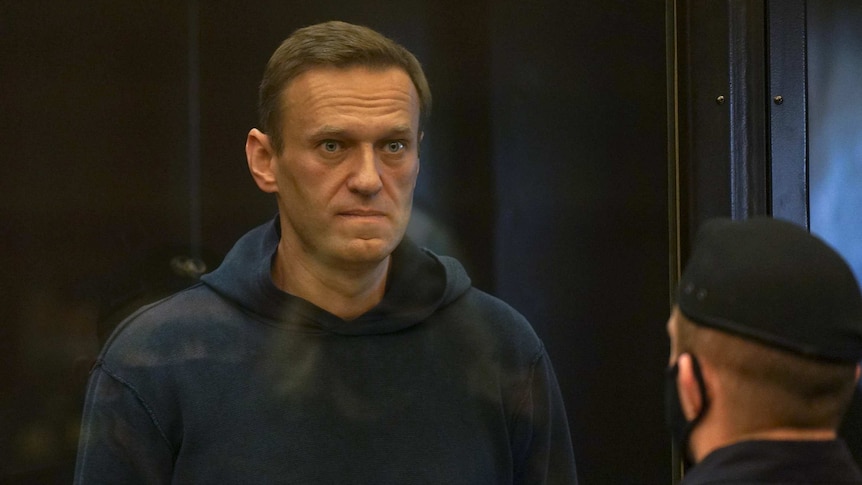 A man in a navy hoodie stares in the distance in a courtroom.