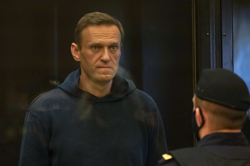 A man in a navy hoodie stares in the distance in a courtroom.