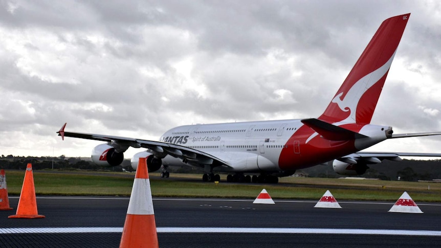 A Qantas plane travels down a runway dotted with traffic cones at Melbourne Airport.