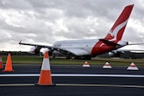 A Qantas plane travels down a runway dotted with traffic comes at Melbourne Airport.