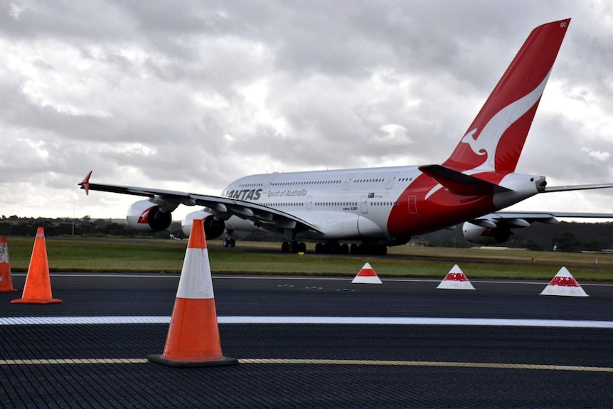 A Qantas plane travels down a runway dotted with traffic cones at Melbourne Airport.