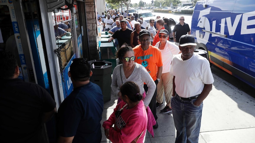 A long line of people wait to buy a lottery ticket from a liquor store.