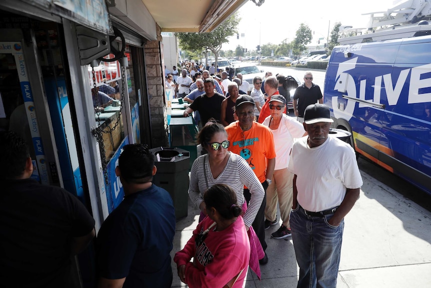 A long line of people wait to buy a lottery ticket from a liquor store.