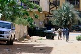 People walk past a military vehicle in Khartoum