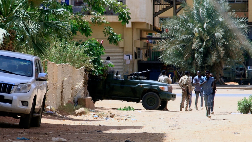People walk past a military vehicle in Khartoum