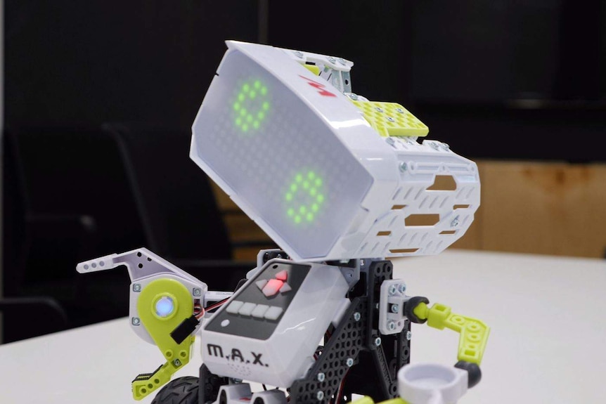 A light grey robot tilting its head. It has pixelated green eyes and claw like hands