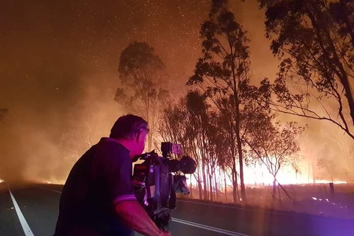 A cameraman filming a bushfire