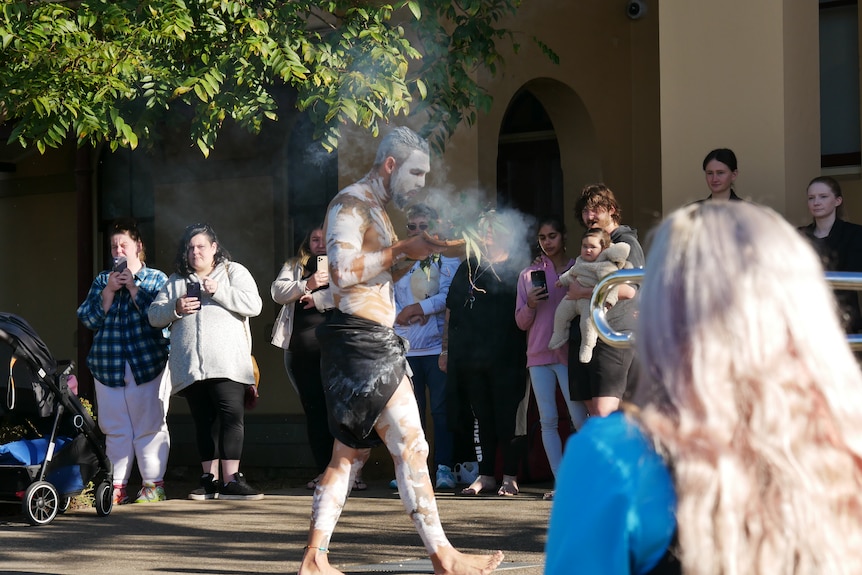 First Nations man conducting smoking ceremony in front of Taree local court. 