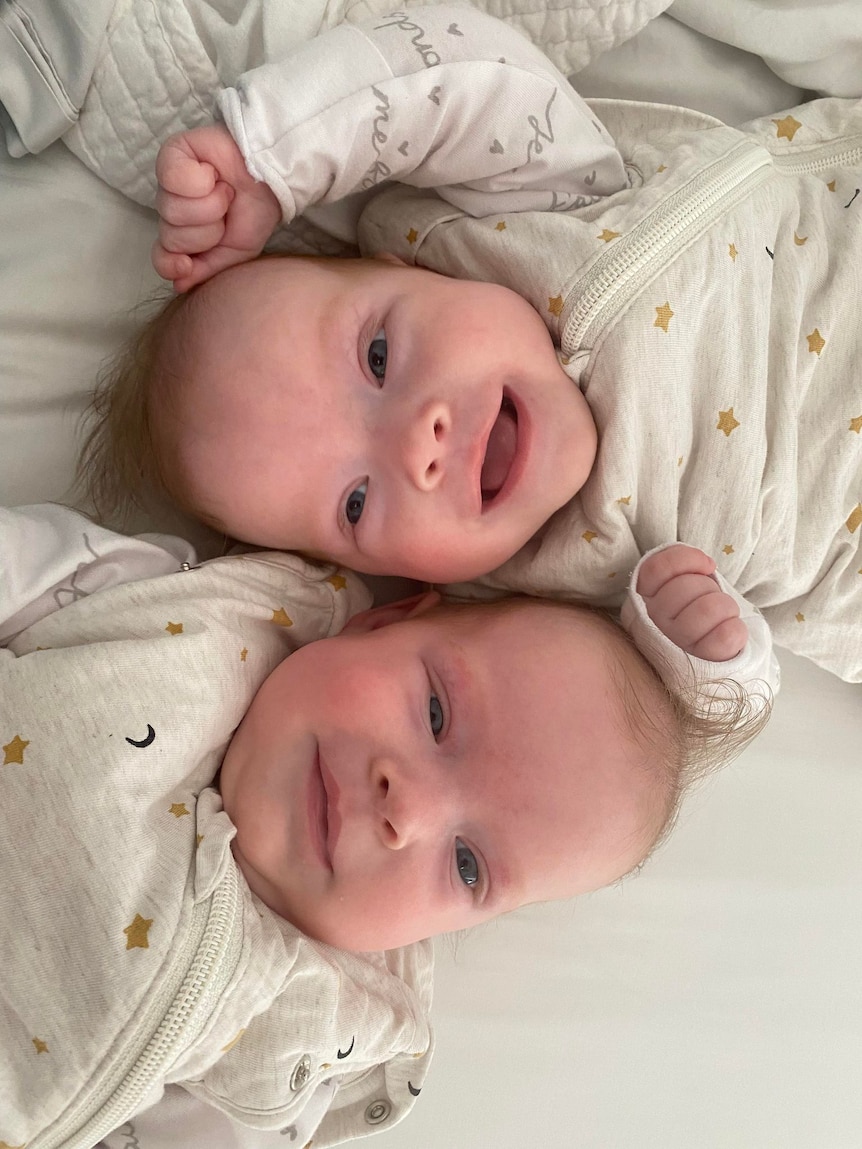Two little babies lying together and smiling.