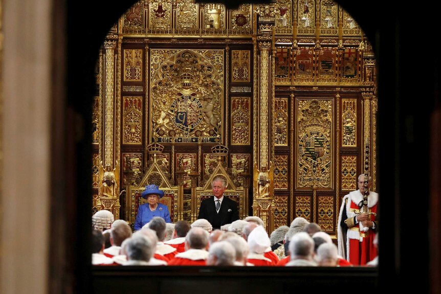 The Queen and Prince Charles sit side by side in front of the House of Lords.