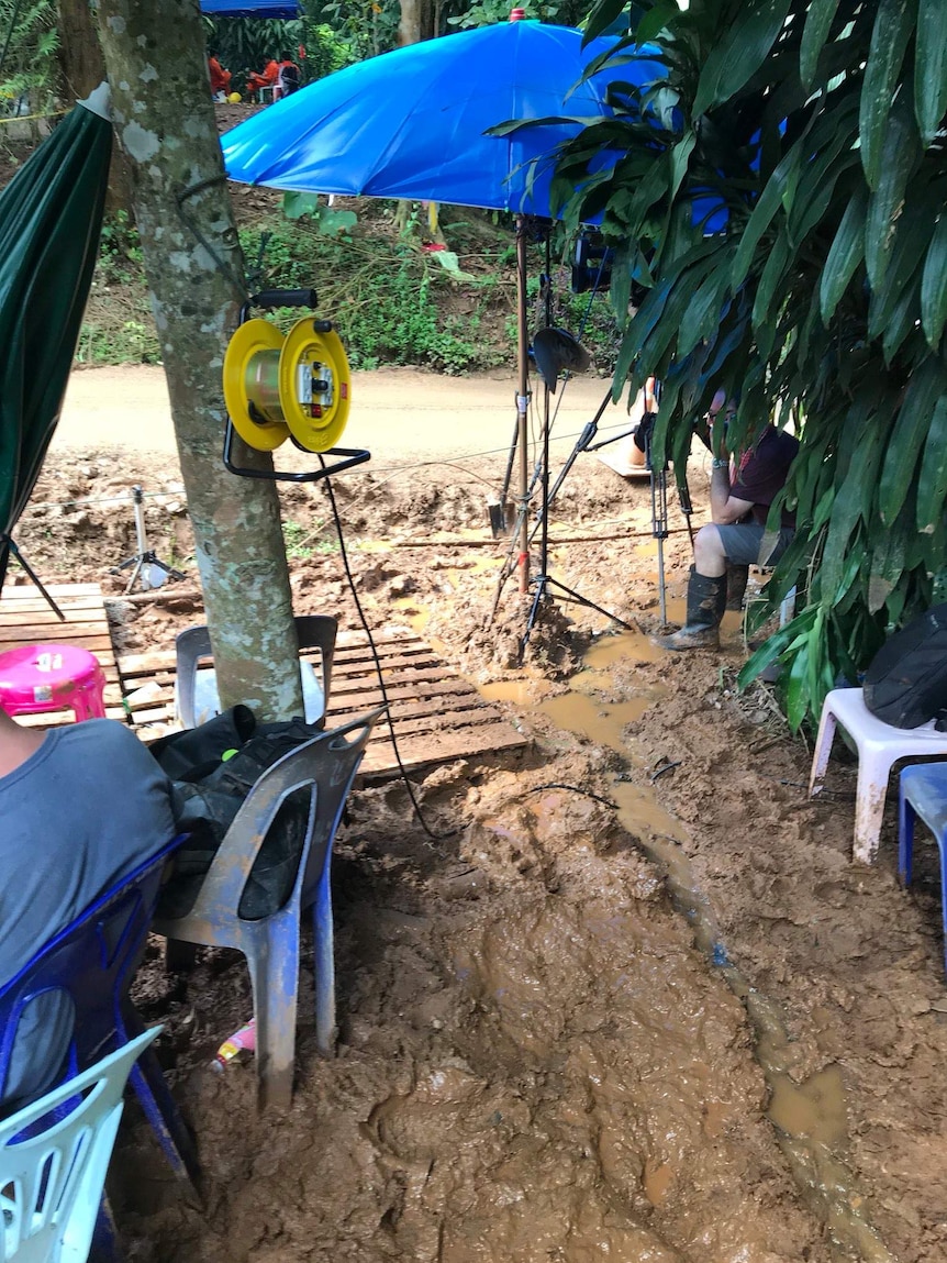 Large blue umbrella, lights and camera tripod in mud.