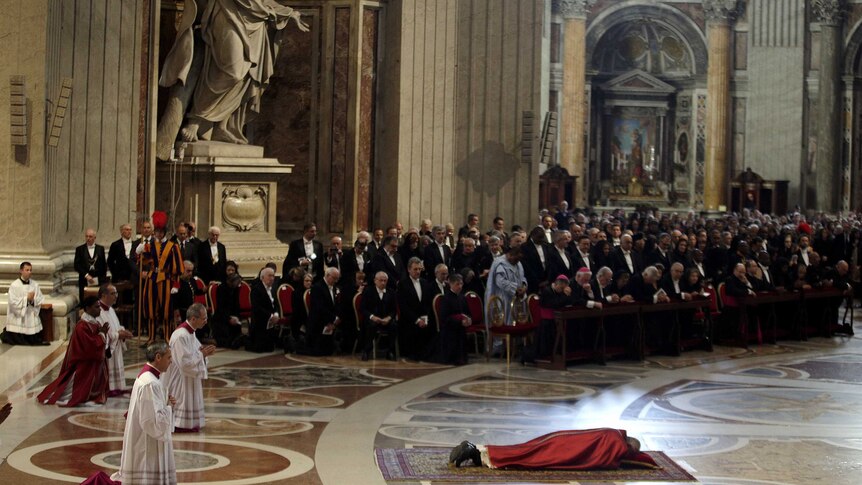 Pope Francis lies as he prays during a Good Friday service