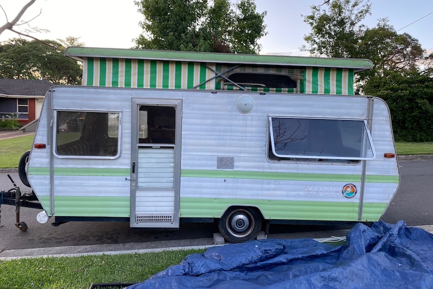 An old green and white caravan parked on the side of a road