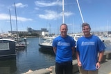 Boatbuilder Joe de Kock and his apprentice Tyrone Bliim stand together at the harbour.