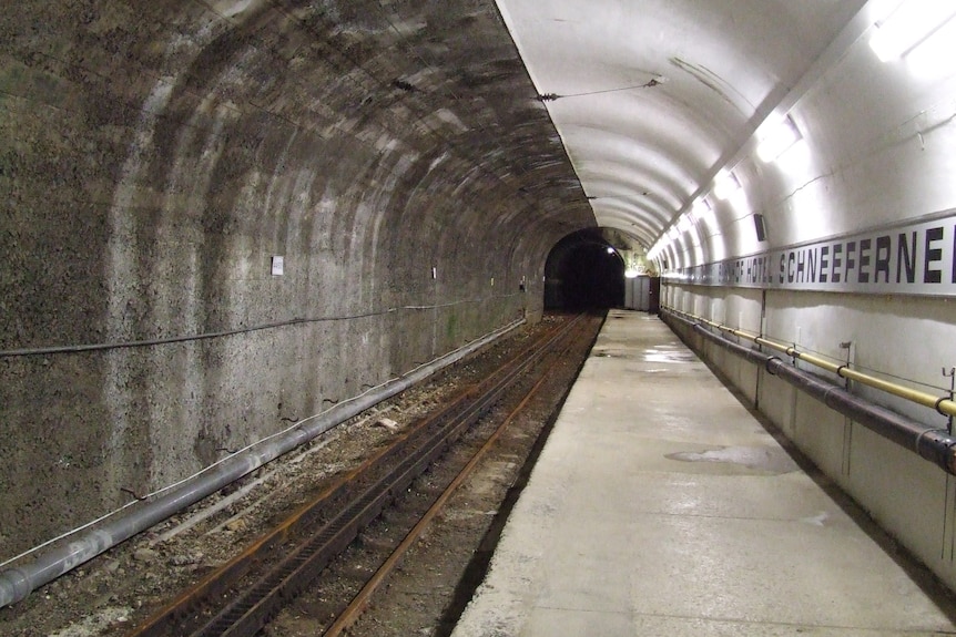 A small underground train station with the platform and tunnel stretching into the distance