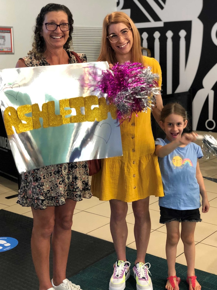 A family wait with signs and pom poms.